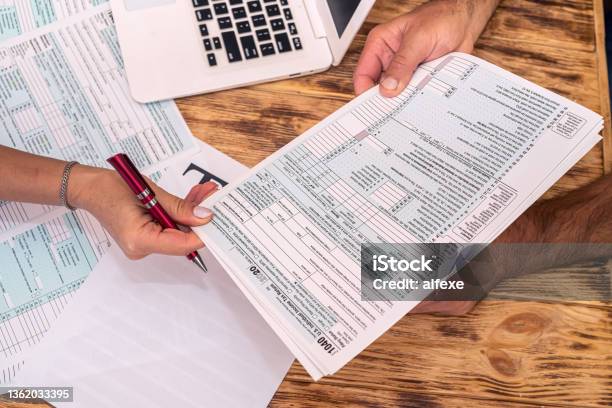 Two Employees At Work Fill Out Tax Forms 1040 At The Office Desk Stock Photo - Download Image Now