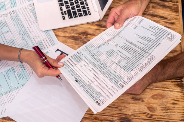 two employees at work fill out tax forms 1040 at the office desk. - tax imagens e fotografias de stock