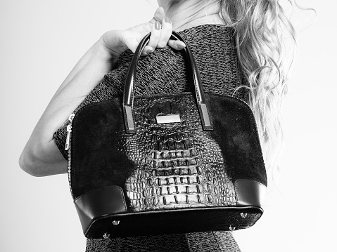 Fashion clothing people concept. Chic woman with black, leather handbag. Female wearing elegant dress.