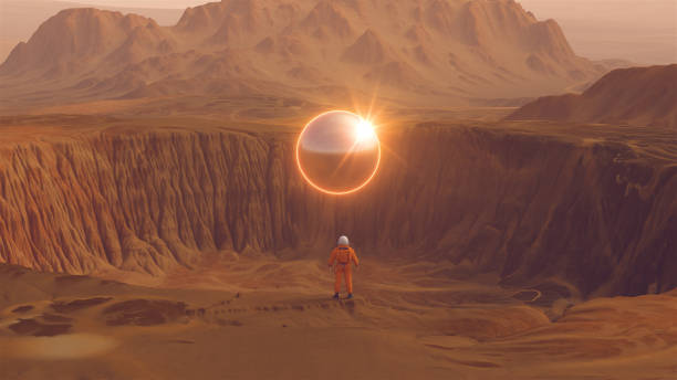 istock Orange Spaceman Spacewoman With Large Alien Silver Sphere Glowing Orange Crater Arid Desert Mountain Sci Fi Astronaut Cosmonaut Landscape Bright Sun Reflection Lens Flare 1362044835