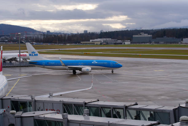 aéroport suisse avec fond de ciel nuageux et voie de circulation humide. - runway airport sky wet photos et images de collection