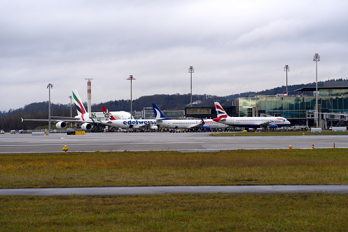 Long distance airplanes at Dock Midfield at Zürich Airport on a rainy and cloudy winter day. Photo taken December 26th, 2021, Zurich, Switzerland.