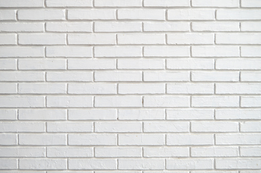 A very light off white colored brick wall with rectangular blocks, textured grungy backgrounds. There is no text, no people and copy space. The masonry joints joint are also grey white in color.