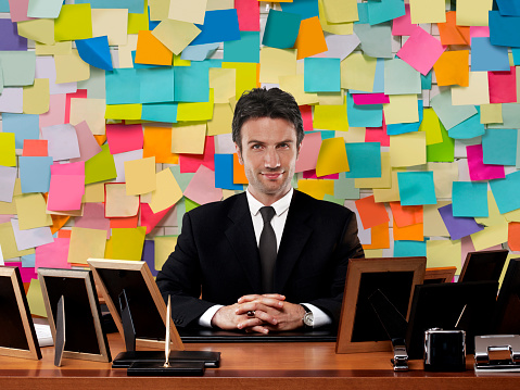 Businessman sitting in front of a wall covered with adhesive notes