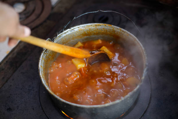 istock Cast iron cauldron boiling a goulash stew over a wood burning stove made from red bricks in the backyard of a rural house in Romania. 1362060629