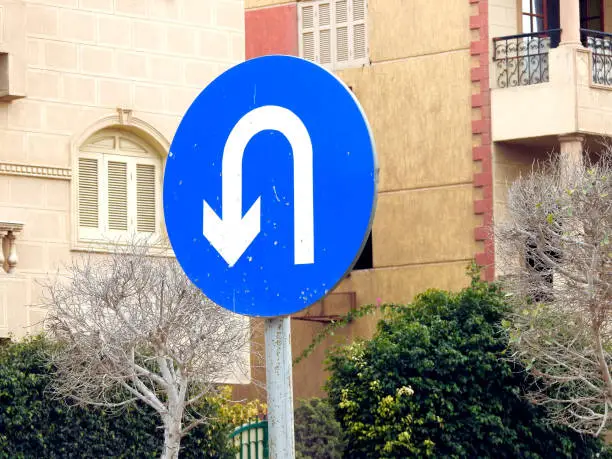 Selective focus of a traffic sign indicates U-turn ahead, turning back, returning symbol on the road for the drivers