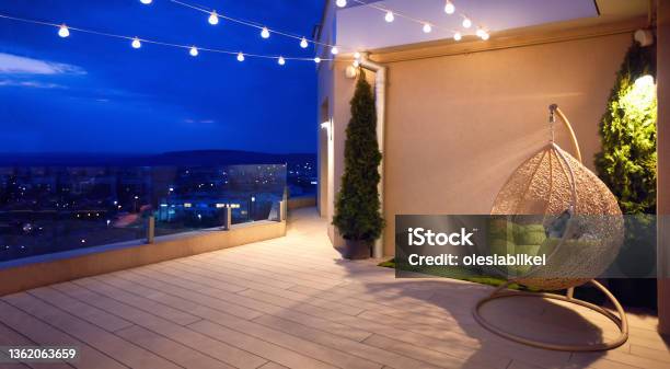 Cozy Rooftop Terrace With Rattan Hanging Chair Garlands And Beautiful Landscape At Night Stock Photo - Download Image Now