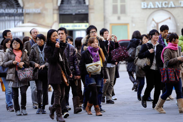 Florence, Italy - November 29 2011:  Japanese tourists during the tour of the historical places and monuments of the city center. An organized tourist group in Piazza della Signoria.
