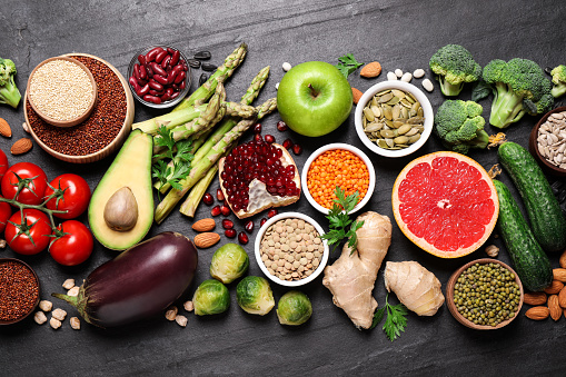 Fresh vegetables, fruits and seeds on black table, flat lay