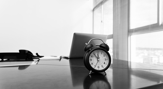 Alarm clock and laptop on office table.