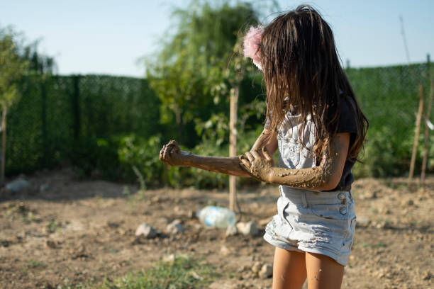Little girl playing with dirt mud in the garden.