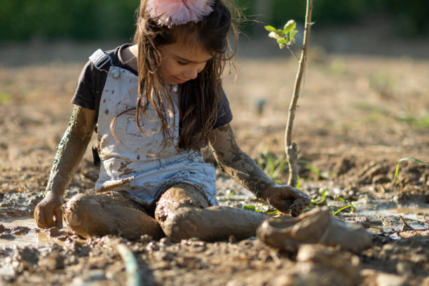 Little girl playing with dirt mud in the garden.