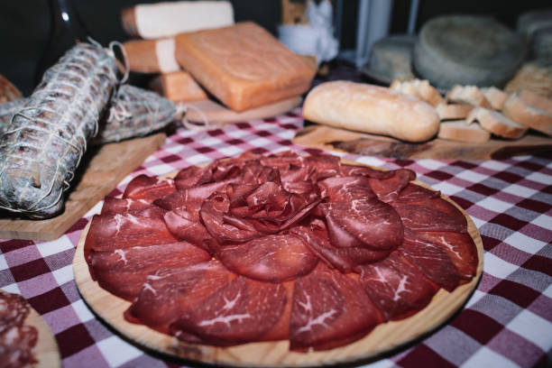 tagliere di bresaola su tavola di prodotti locali locali - bresaola foto e immagini stock