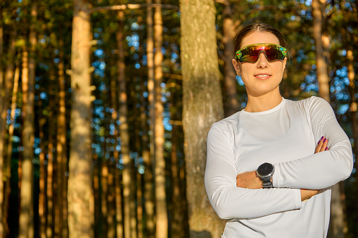 Happy athletic woman in sports glasses is getting ready to start training outdoors and get a boost of energy for the whole day. Concept of sports and a healthy lifestyle