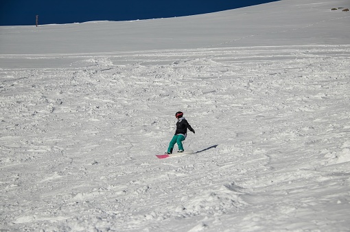 girl on a snowboard rides down the side of the mountain