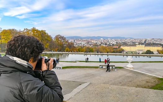 Vienna, Austria - Novermber 2019: Person taking pictures with a camera in the grounds of the Schonbrunn Palace in Vienna.