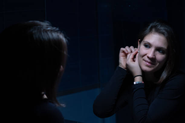 uma jovem adulta olhando para o rosto através do espelho antes da maquiagem - mirror women kissing human face - fotografias e filmes do acervo