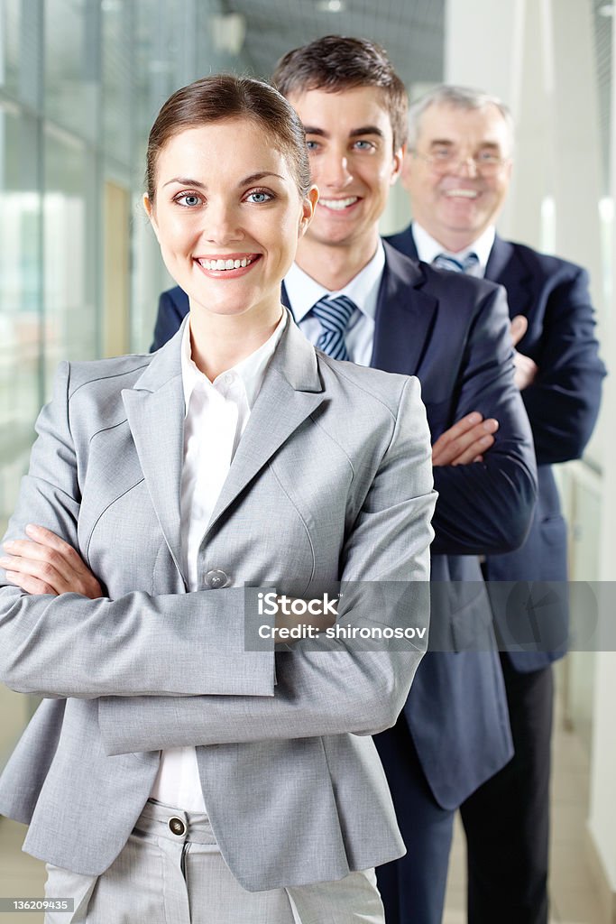 Happy leader Smiling businesswoman looking at camera with two men behind Adult Stock Photo