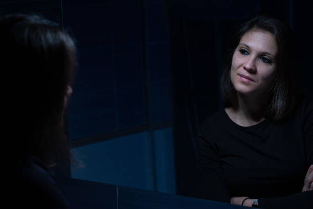 młoda dorosła kobieta patrząca na swoją twarz przez lustro przed makijażem - mirror women kissing human face zdjęcia i obrazy z banku zdjęć