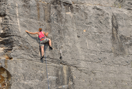 Rovinj, Istria, Croatia - June 25, 2017:  Woman in red top Rock Climbing on Rock Face.,