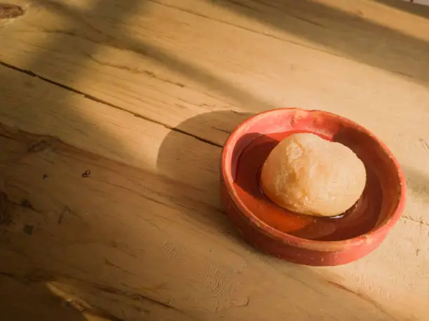 Photo of nolen gur rosogolla or rasgulla served on plate. brown spongy bengali indian traditional sweet made from cottage cheese and jaggery. winter special delicacy.