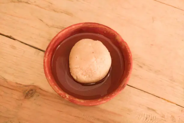 Photo of nolen gur rosogolla or rasgulla served on plate. brown spongy bengali indian traditional sweet made from cottage cheese and jaggery. winter special delicacy.