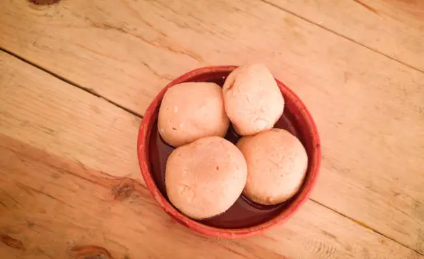 Photo of nolen gur rosogolla or rasgulla served on plate. brown spongy bengali indian traditional sweet made from cottage cheese and jaggery. winter special delicacy.