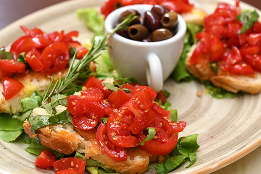 High-angle view of homemade Italian bruschetta with tomatoes, basil and olives on a plate in Tuscany, Italy, Europe