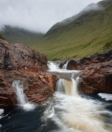 Small mountain river with waterfalls and mountains covered with clouds. River Etive, Highlands, Scotland