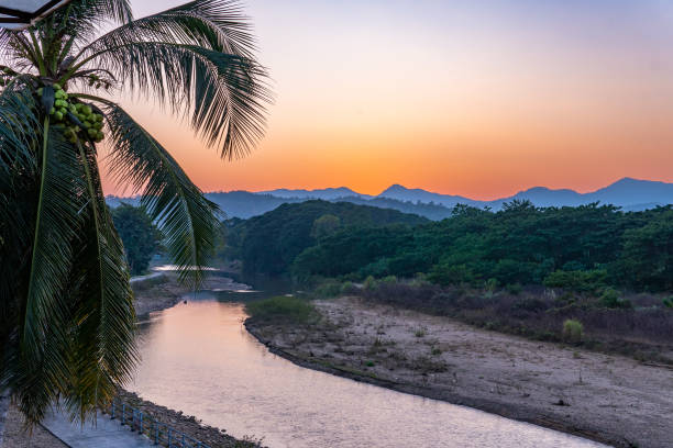 Sunset over the mountains with river and palm tree stock photo