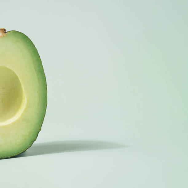 istock Macro shot of avocado half against the light green background. 1362101415