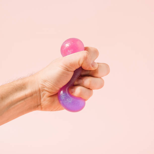 istock Hand squeezing violet purple glitter slime on a pastel pink background. 1362102589