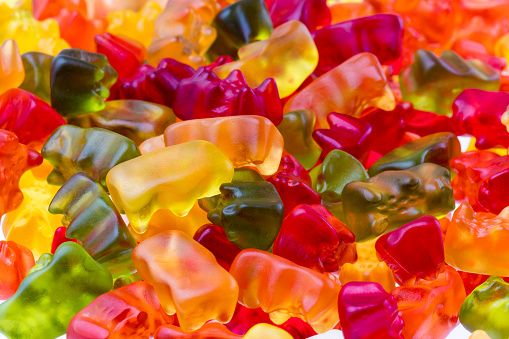 Gummy bear in row on a white background, focus on the red one.