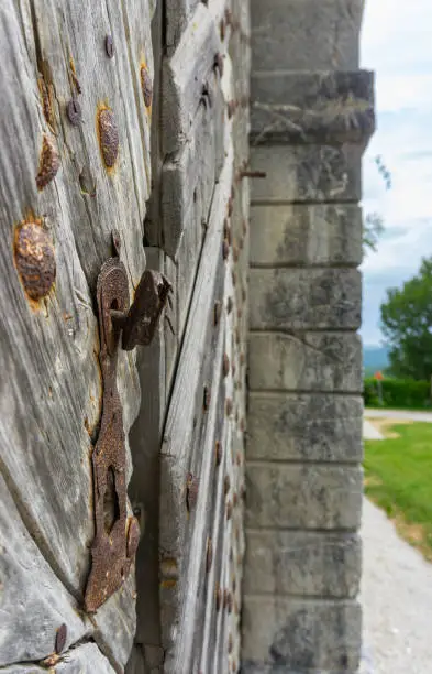 Photo of Focus on rusted handle and bolts on wooden old patterned doors, with blurred bakcground