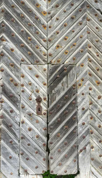 Photo of Splendid old doors with bolts and cast-iron handle and a special wooden pattern on the doors