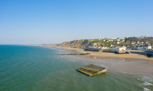 This landscape photo was taken in Europe, in France, in Normandy, in Arromanches les bains, in summer. We see the artificial port of the city of Arromanches les Bains, under the Sun.