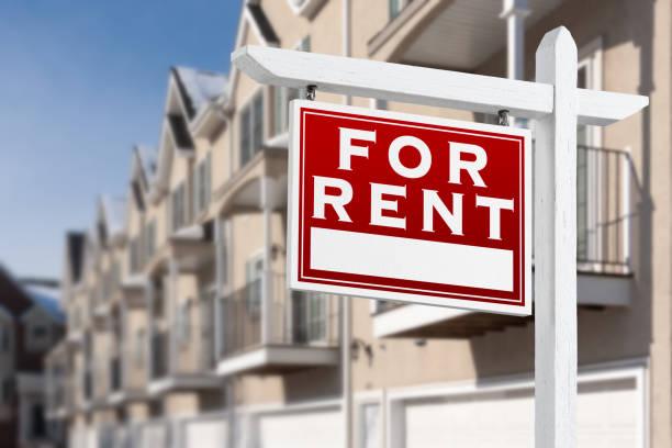 for rent real estate sign in front of a row of apartment condominiums balconies and garage doors. - rental stockfoto's en -beelden