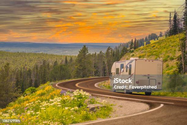 Camper Driving Down Road In The Beautiful Countryside Among Pine Trees And Flowers Stock Photo - Download Image Now