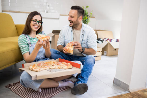istock Young couple eating pizza while moving into a new apartment 1362139485