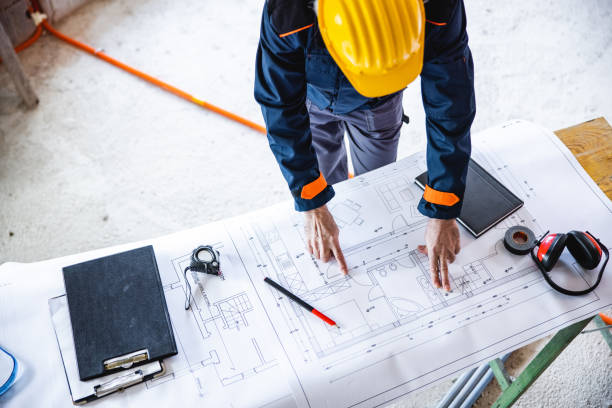 istock Close up overhead view of construction worker studying blueprints for a new building 1362142528