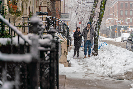 A young couple, man, and woman on the street in Manhattan in snowy winter day