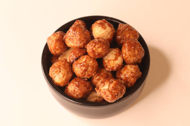 istock Selective focus of many candied macadamia nuts spinning in a small bowl. 1362143286
