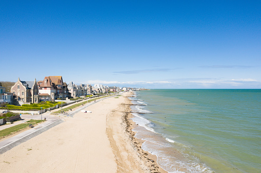 This landscape photo was taken in Europe, in France, in Normandy, towards Ouistreham, in summer. We see the long beach of the Overlord landing of fine sand of Sword beach in Lion-sur-Mer, under the Sun.