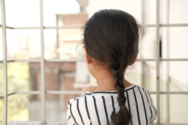 istock sad child kid girl looking through window 1362152300