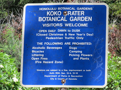 A bright blue information sign, at Koko Crater  botanical garden, with white lettering explaining to visitors and tourist the footpath to the Hawaiian Section of plants on display.