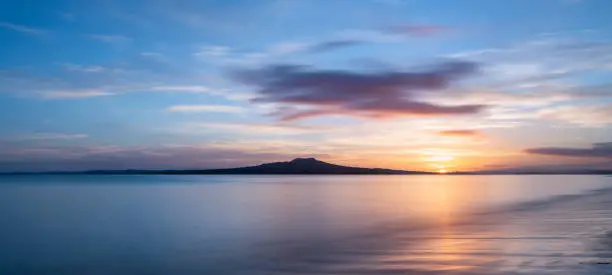 Photo of Sun rising over the Rangitoto Island at Milford Beach, Auckland.