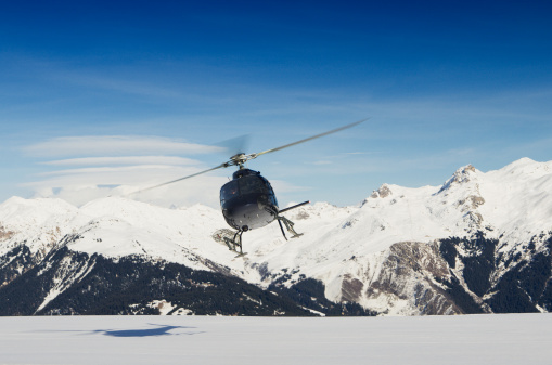 A mountain rescue helicopter in flight by snowy mountains