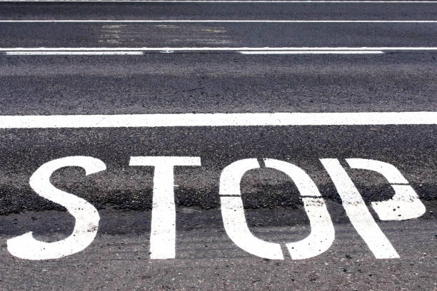 above view of word STOP and stop bar on asphalt road