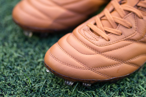 A kangaroo leather football shoe in vintage brown colorway with classic style stitching pattern. Close-up at the upper detail. Sport equipment object photo.