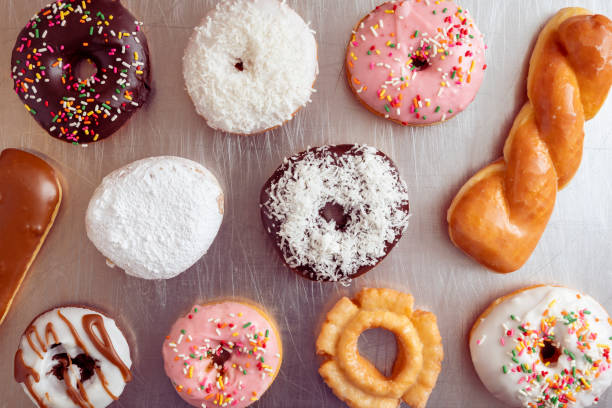 Top view of many different kind of donuts on a scratched metal plate